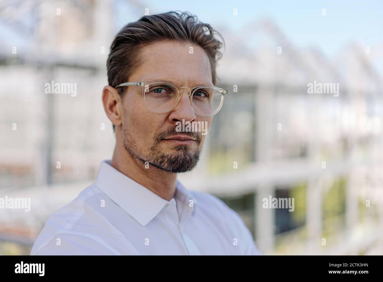 Primo piano di un serio uomo professionista che indossa occhiali in vivaio di piante Foto Stock