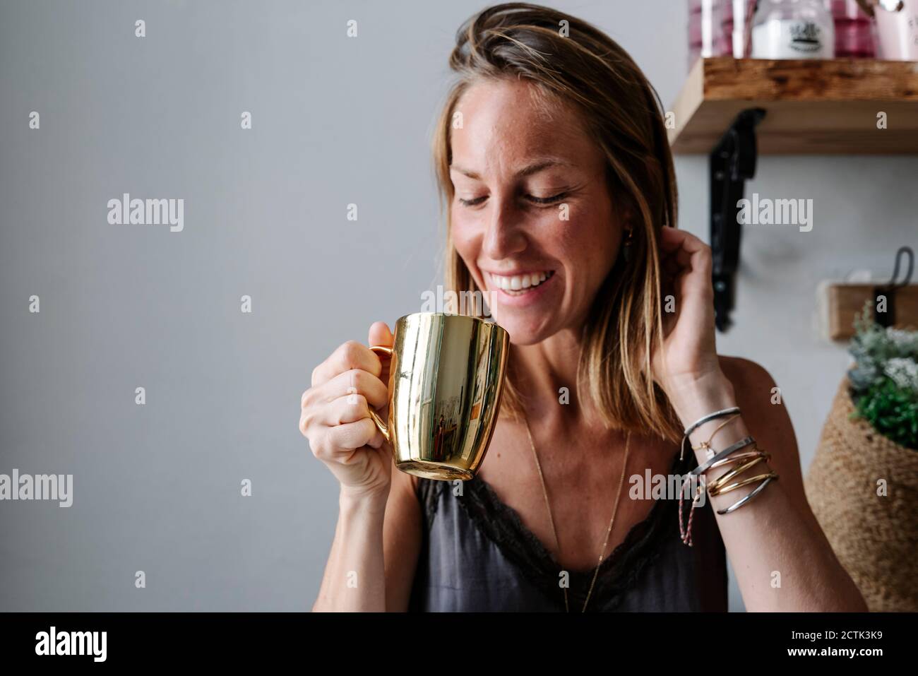 Sorridente bella donna che beve dalla tazza d'oro Foto Stock