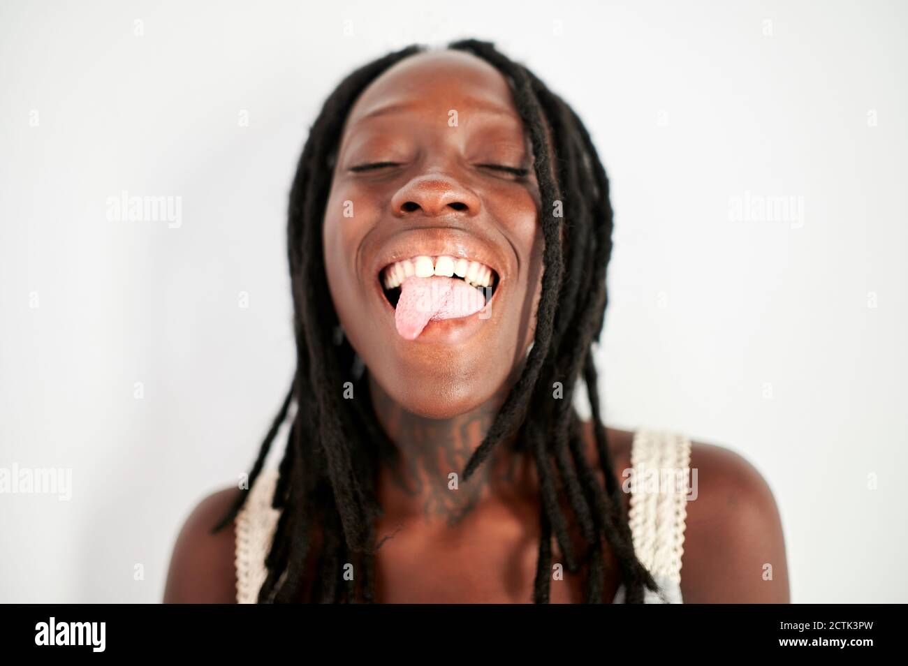 Giovane donna che si stacca la lingua su sfondo bianco Foto Stock