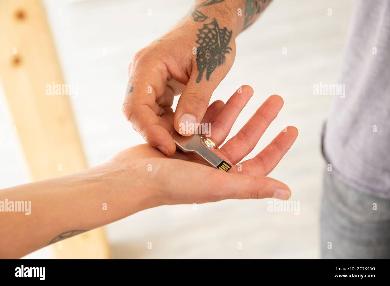 Primo piano della mano dell'uomo che dà la chiave USB alla moglie dentro nuova casa Foto Stock