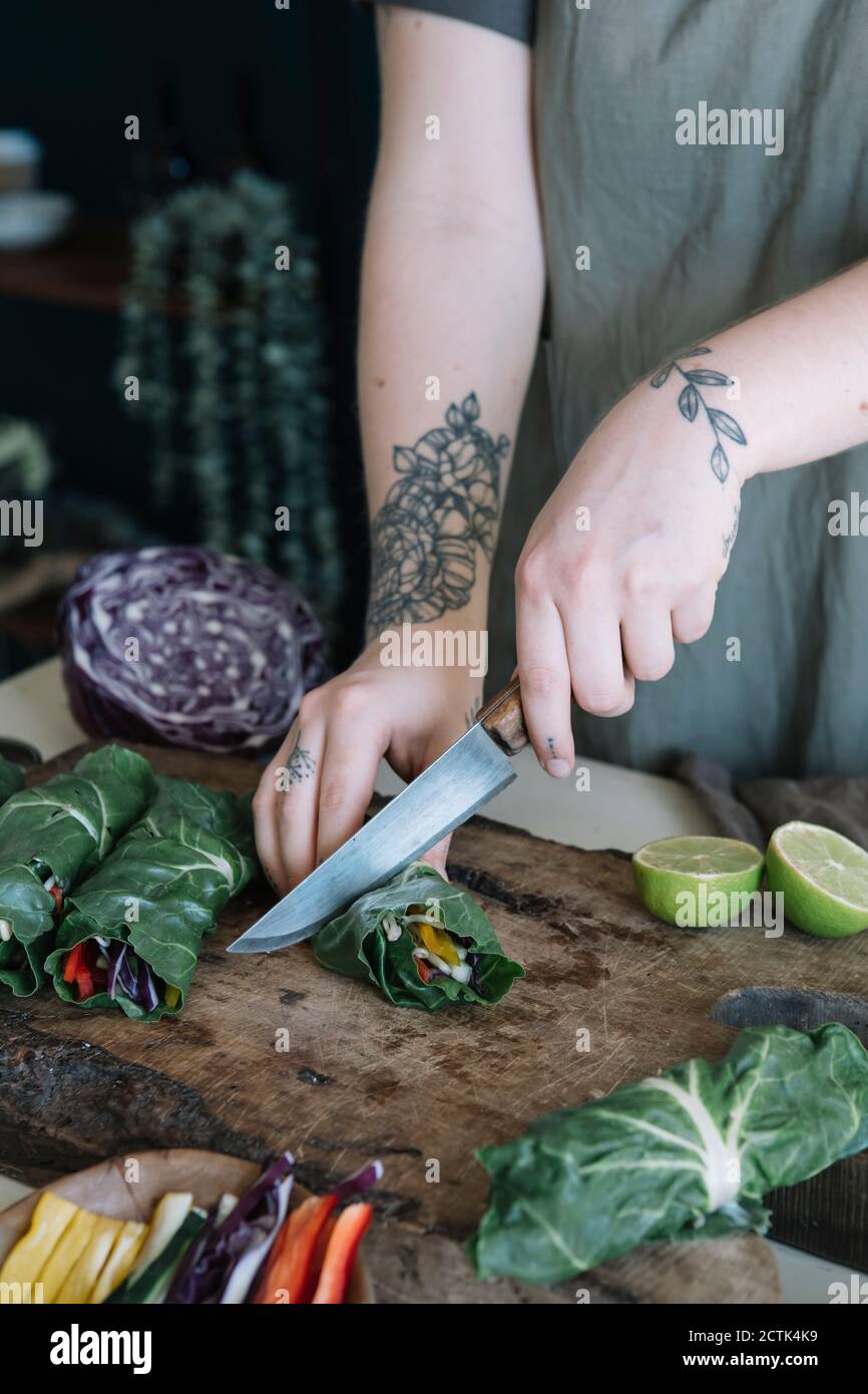 Giovane donna che taglia il rotolo vegano con tagliere vegetableson Foto Stock