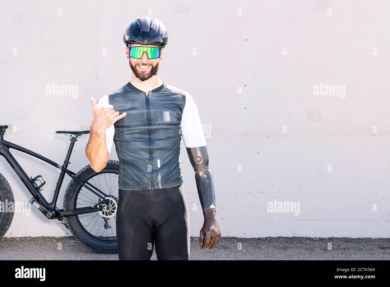 Sorridente atleta adattivo maschile gesturing mentre si sta in piedi contro il muro Foto Stock