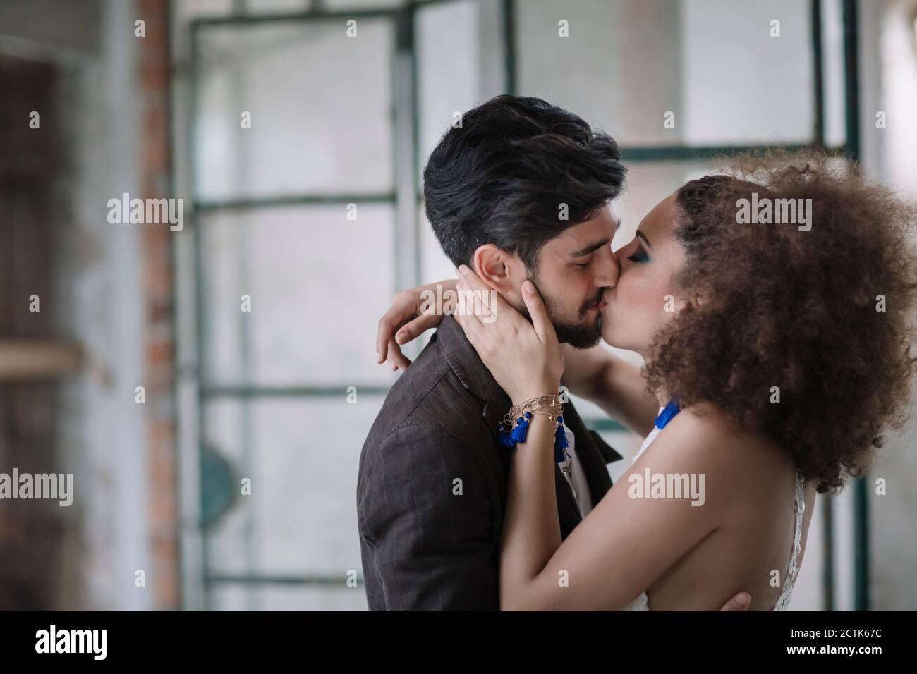 Appena sposato coppia baciarsi mentre si sta in piedi in camera Foto Stock
