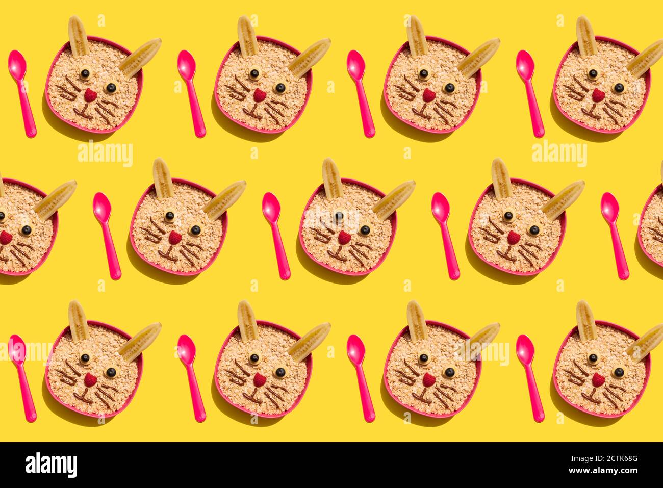 Modello di ciotole di porridge di avena con facce di coniglio fatte di banane, cioccolato, lamponi e mirtilli Foto Stock