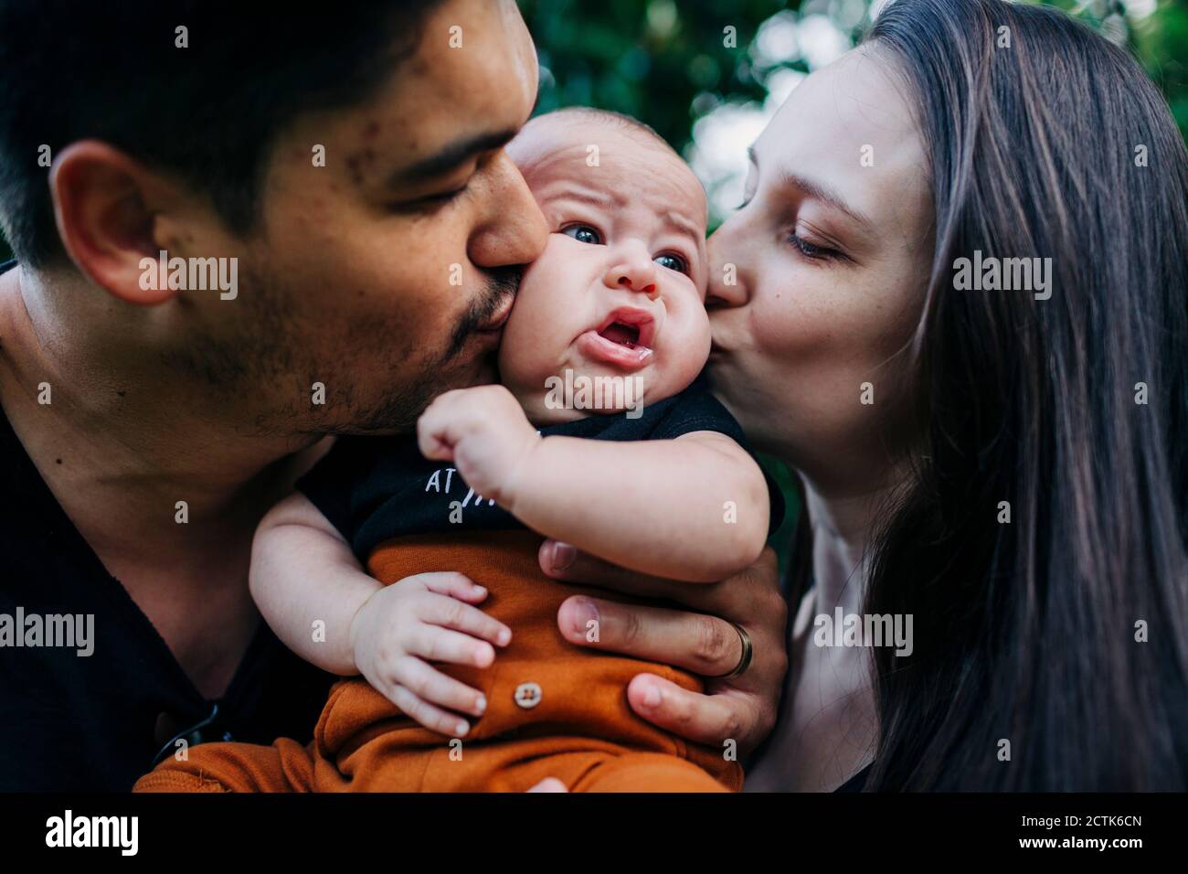 I giovani genitori baciano il figlio del bambino Foto Stock
