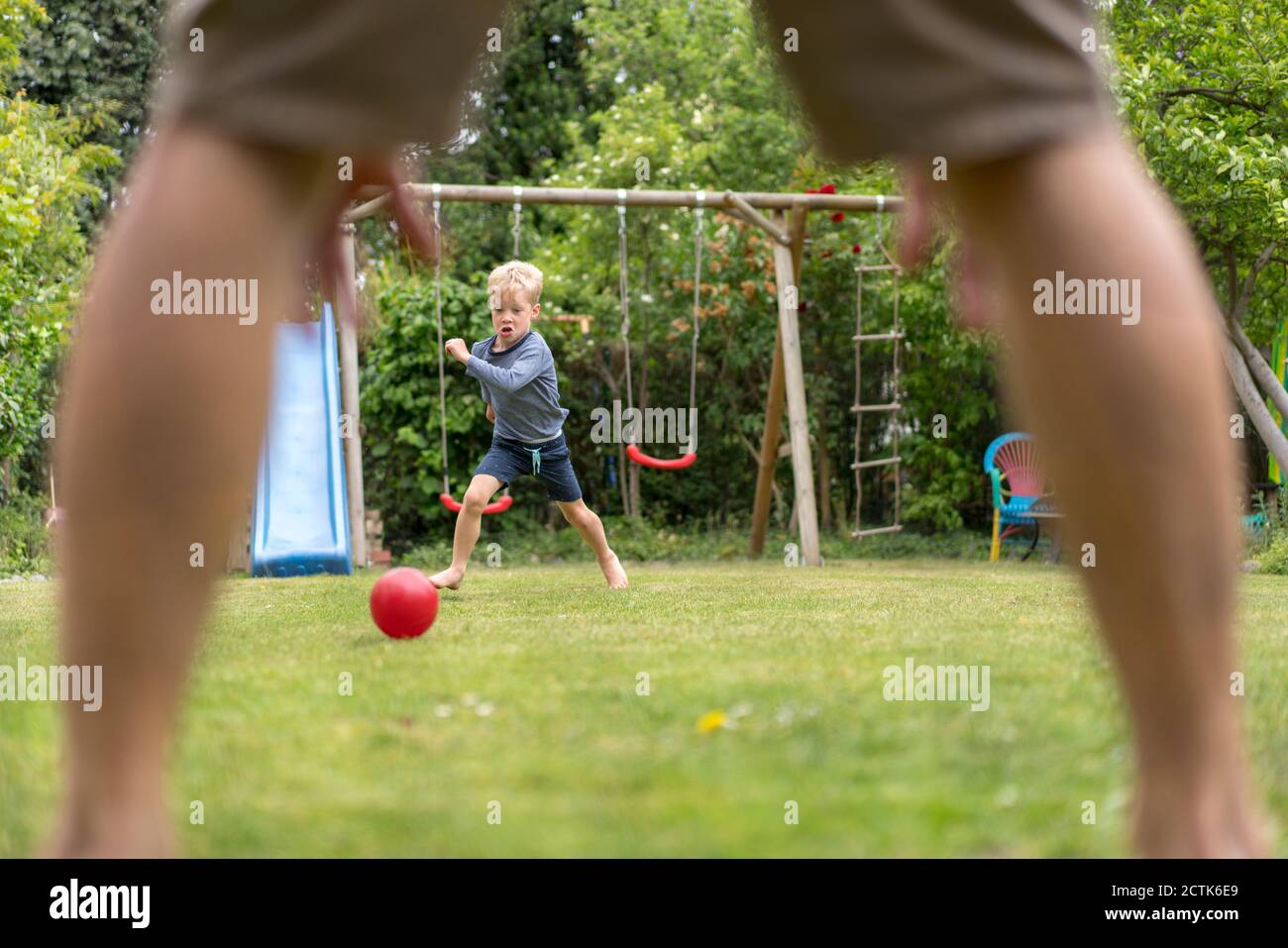 Ragazzo che gioca a calcio con il padre nel cortile posteriore durante il fine settimana Foto Stock