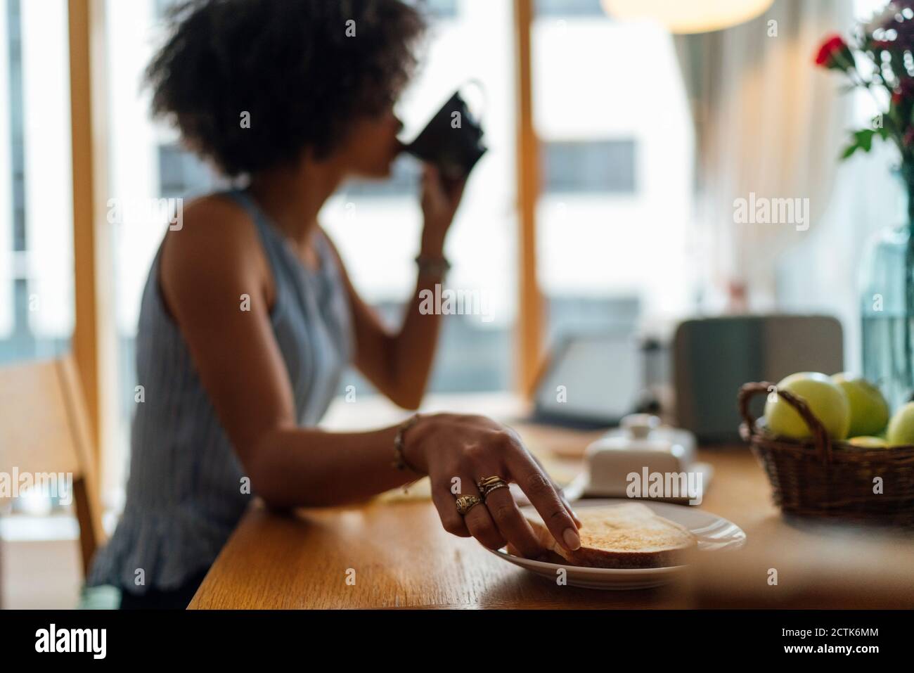 Giovane donna che ha la colazione sul tavolo a casa Foto Stock