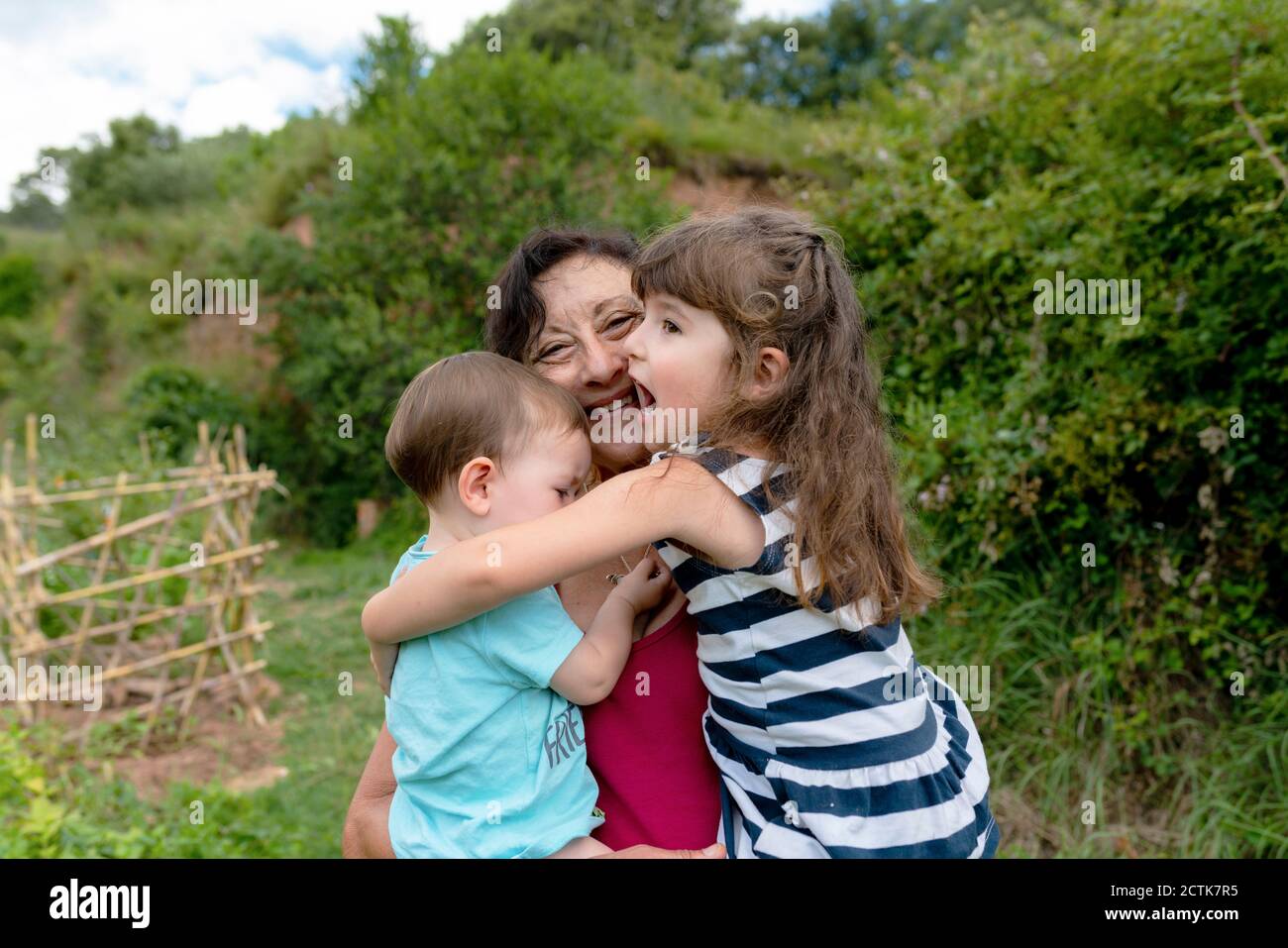 Nonna felice che abbraccia le nipote nel campo Foto Stock
