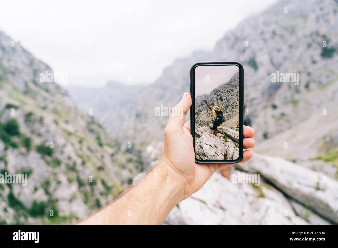 L'uomo tiene il telefono mentre scatta la foto della donna spensierata a Ruta del Cares, Asturias, Spagna Foto Stock