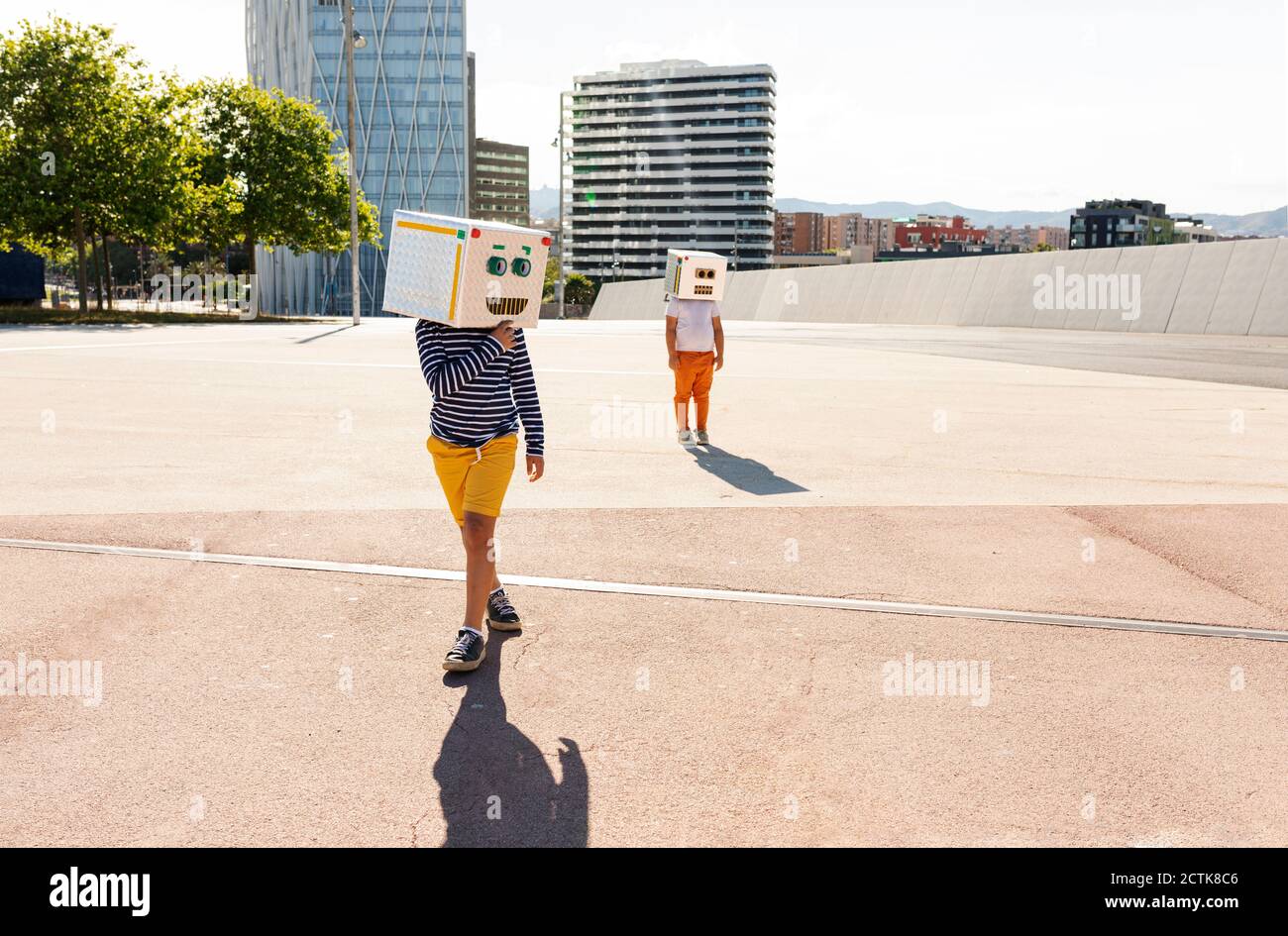 Ragazzi che indossano maschere robot in posa su strada in città durante giorno di sole Foto Stock