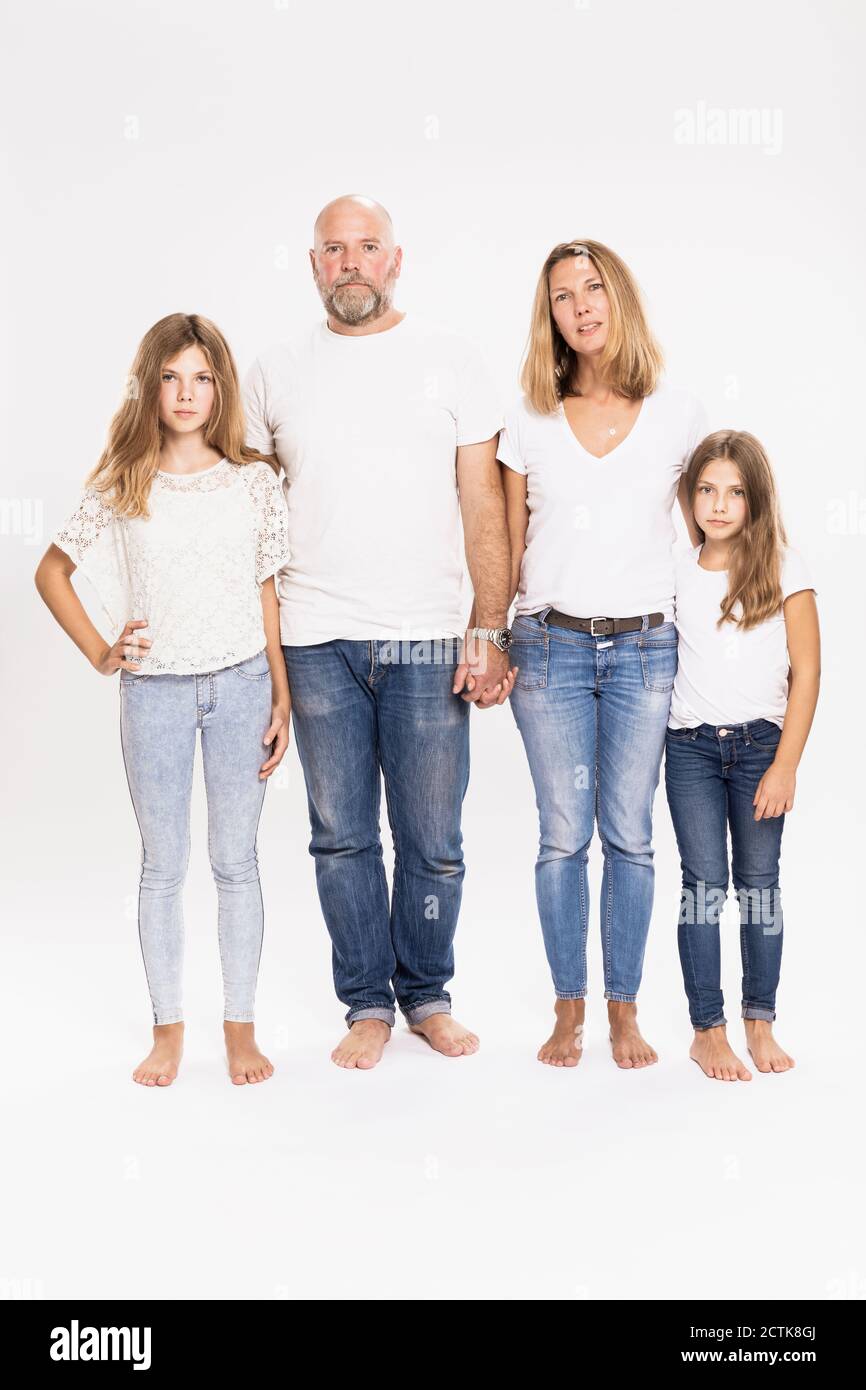 Famiglia che indossa t-shirt e jeans in piedi su sfondo bianco Foto Stock