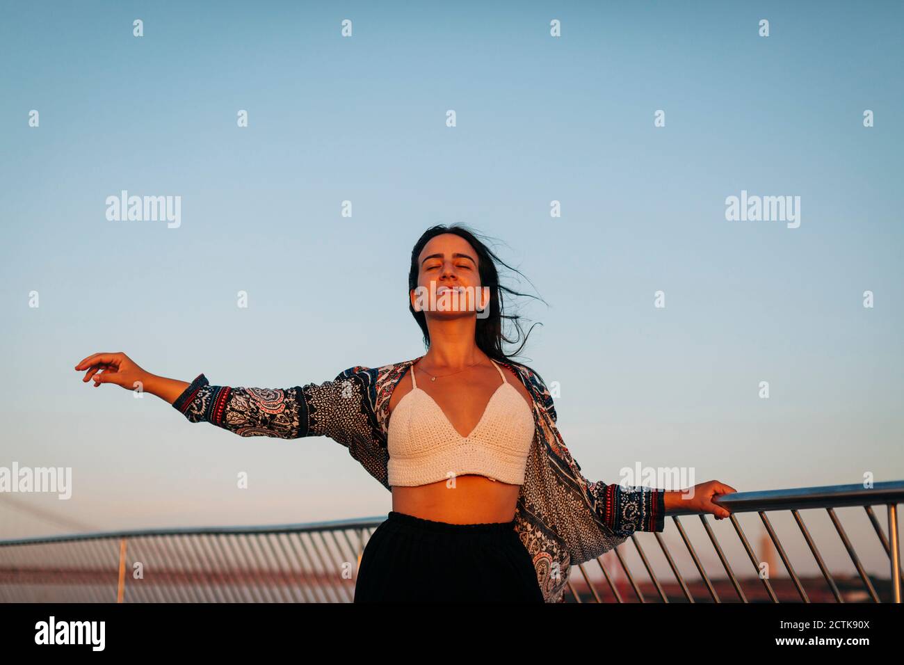 Bella donna con le braccia sollevate in piedi contro il cielo limpido Foto Stock