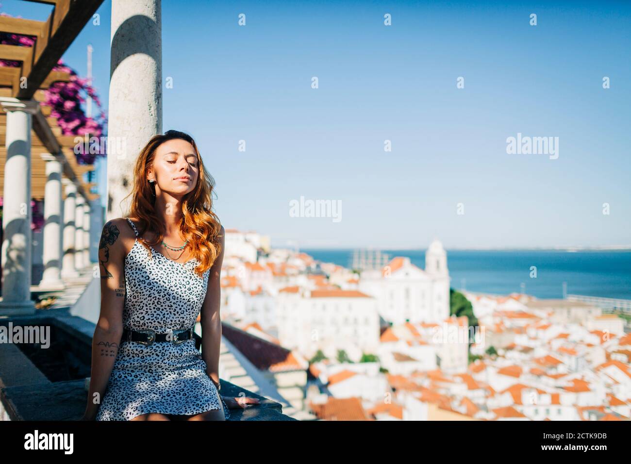 Donna che riposa mentre siede sul muro di contenimento ad Alfama, Lisbona, Portogallo Foto Stock