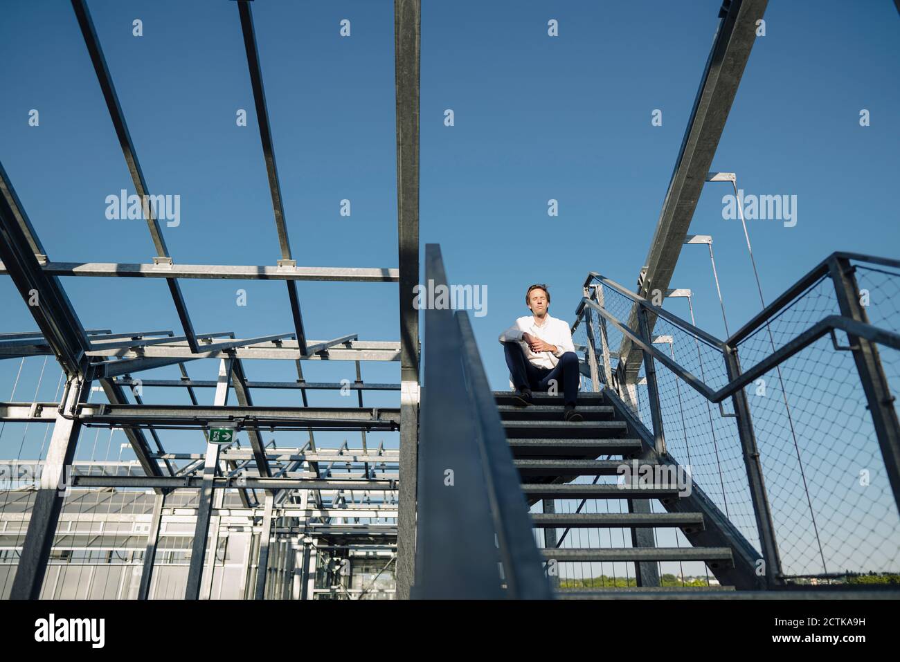 Scienziato seduto sulle scale sotto il cielo blu Foto Stock