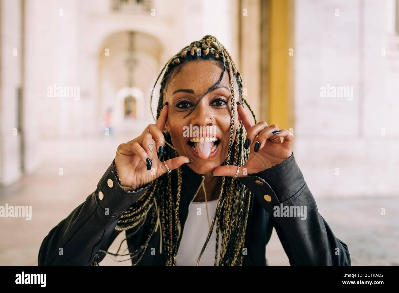 Donna allegra con lunghi capelli intrecciati che aderiscono alla lingua Foto Stock