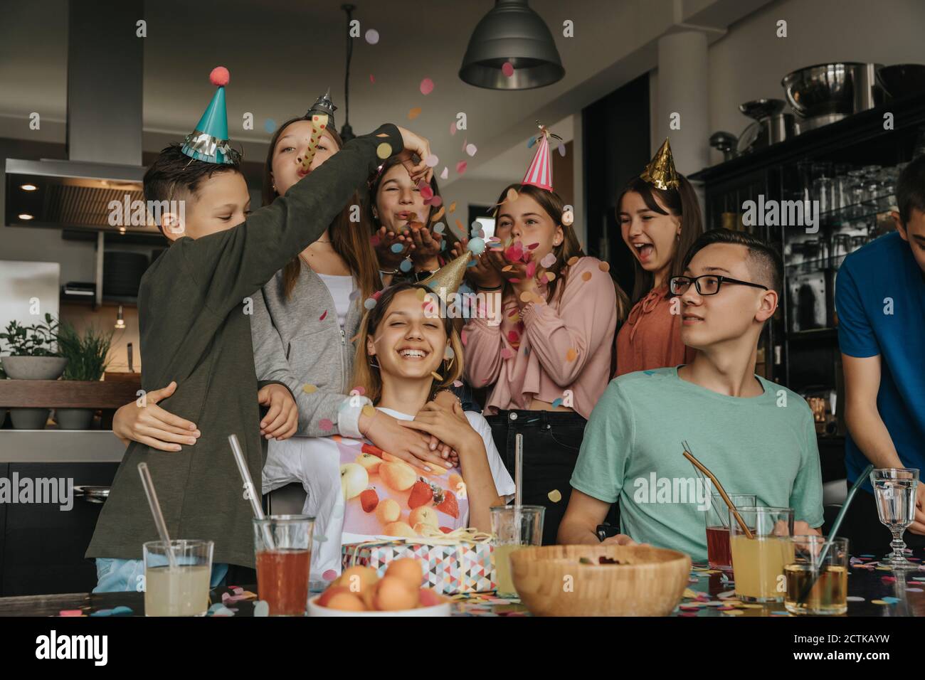 Amici felici che gettano i confetti sulla ragazza teenage nella festa di compleanno a casa Foto Stock