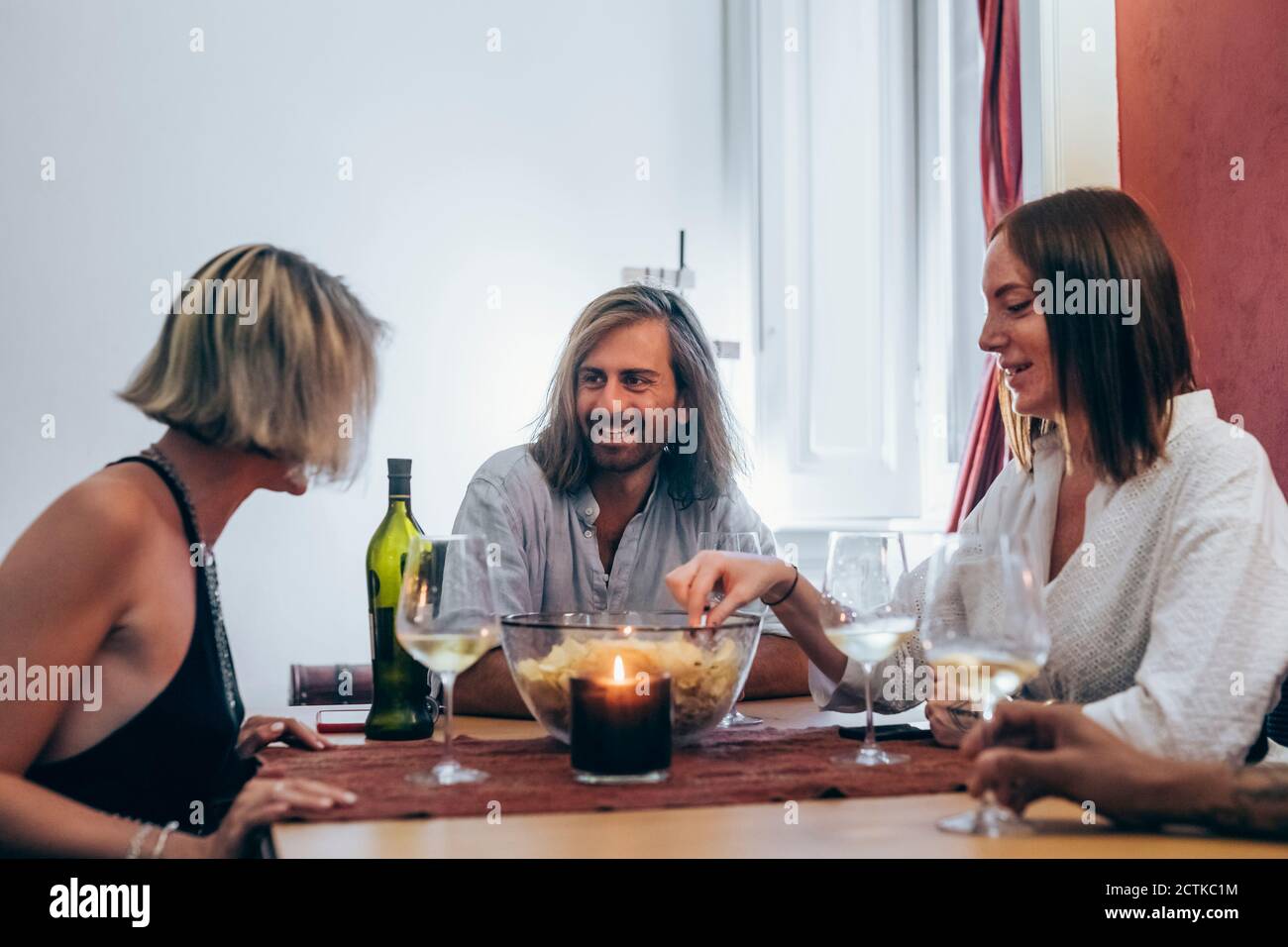 Sorridendo giovani amici che hanno vino a tavola durante la riunione sociale Foto Stock
