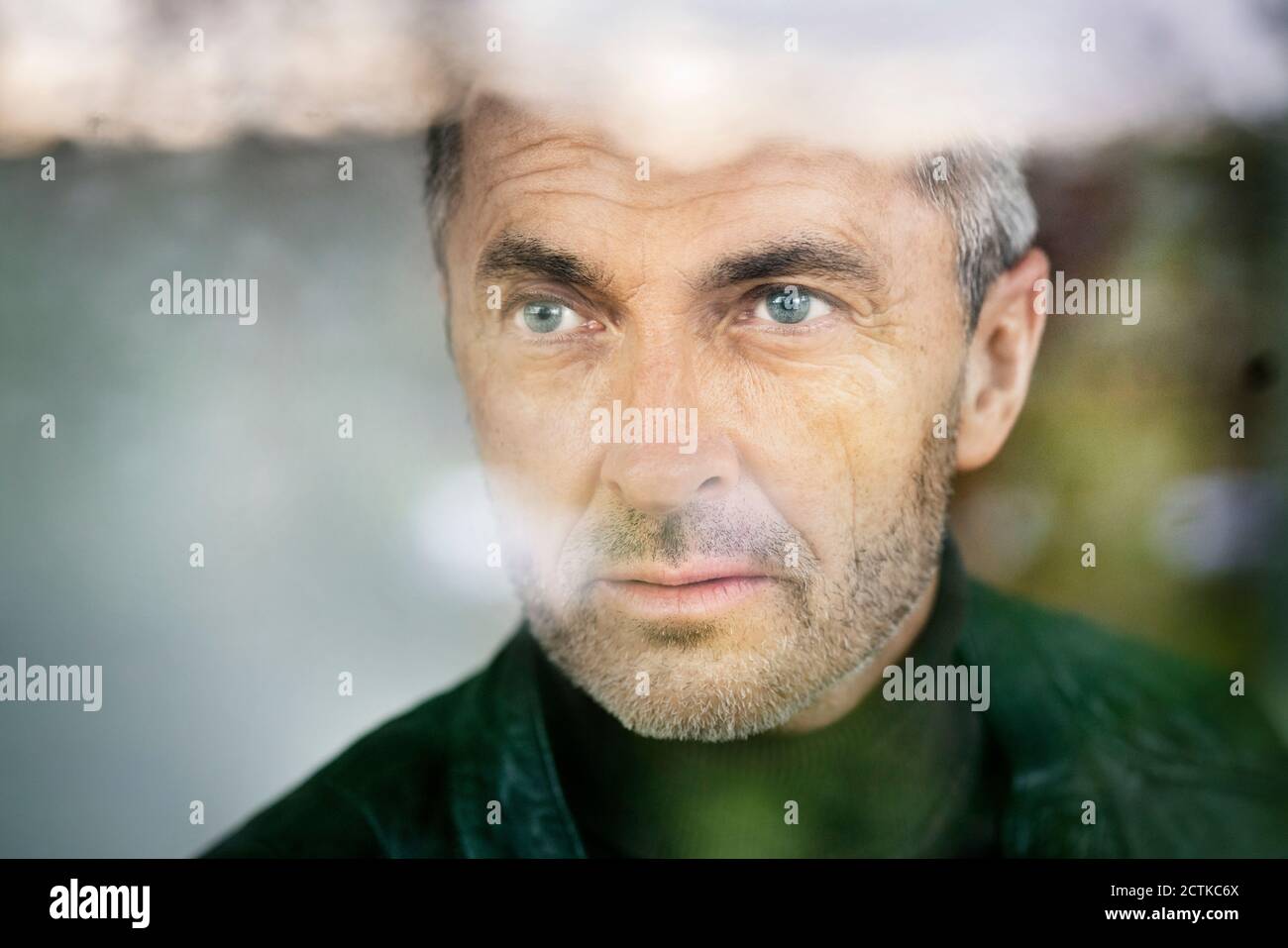 Primo piano di uomo d'affari premuroso con gli occhi blu che guardano via dentro ufficio Foto Stock