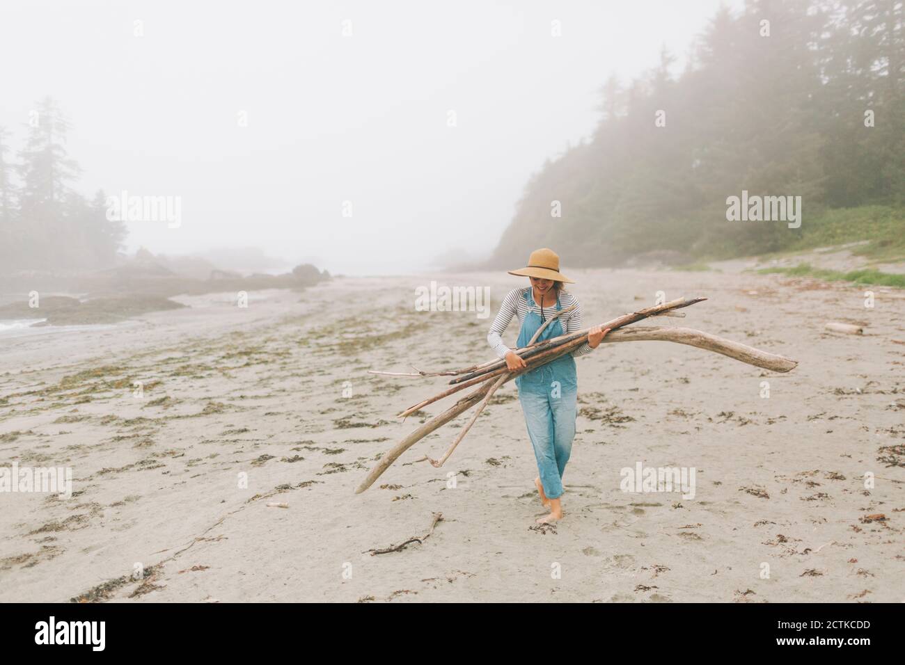 Donna che indossa cappello con i log mentre cammina in spiaggia Foto Stock