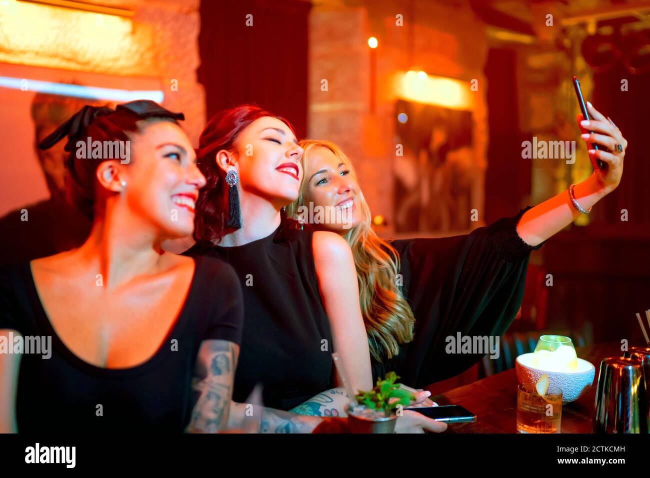 Amici che prendono selfie mentre si levano in piedi al banco del bar nel pub Foto Stock Amici che prendono selfie mentre si levano in piedi al banco del bar nel pub Foto Stock