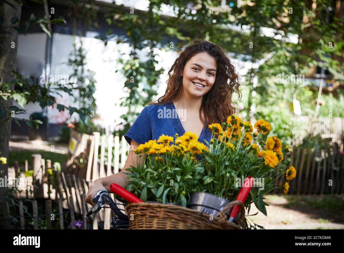 Giovane donna con vasi di fiori in cesto di bicicletta Foto Stock