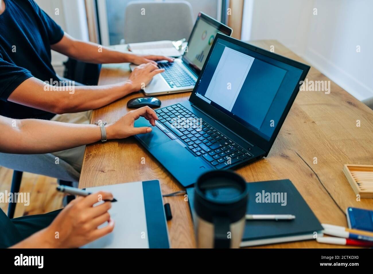 I progettisti Web lavorano mentre utilizzano il computer portatile alla scrivania dell'ufficio Foto Stock