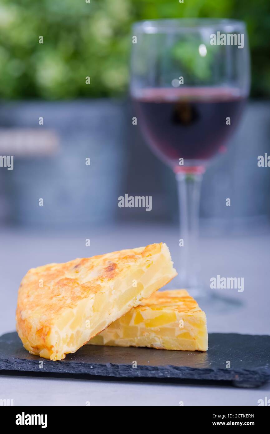 Primo piano di una deliziosa fetta di omelette spagnola in cima a un altro su un piatto scuro su uno sfondo fuori fuoco. Cucina spagnola e tradizionale Foto Stock