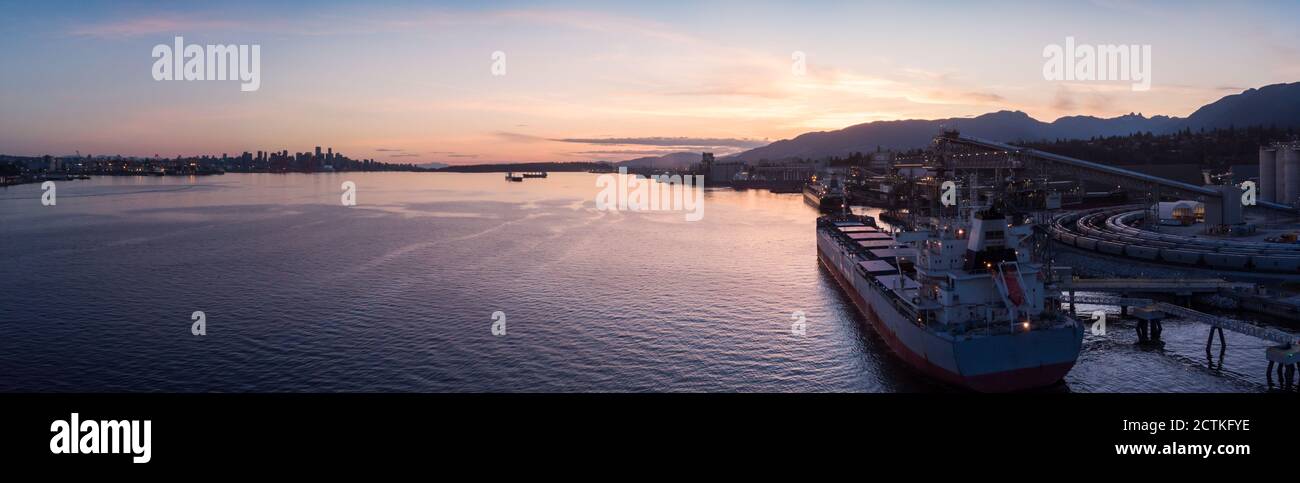 Drone aereo di un terminale di carico marino industriale con navi da carico a Vancouver, BC, Canada al tramonto. Foto Stock