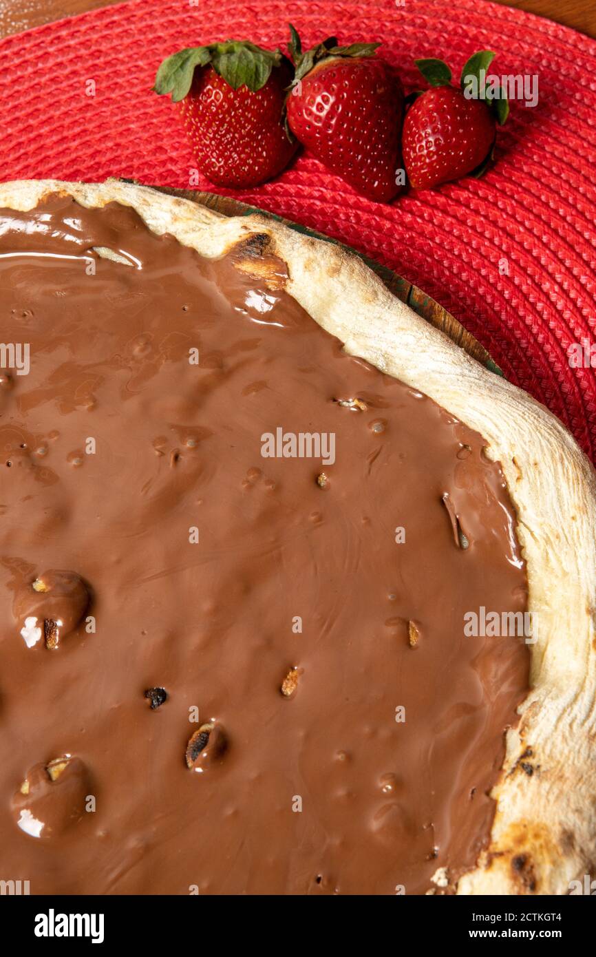 Pizza al cioccolato e fragole su tavola di legno Foto Stock