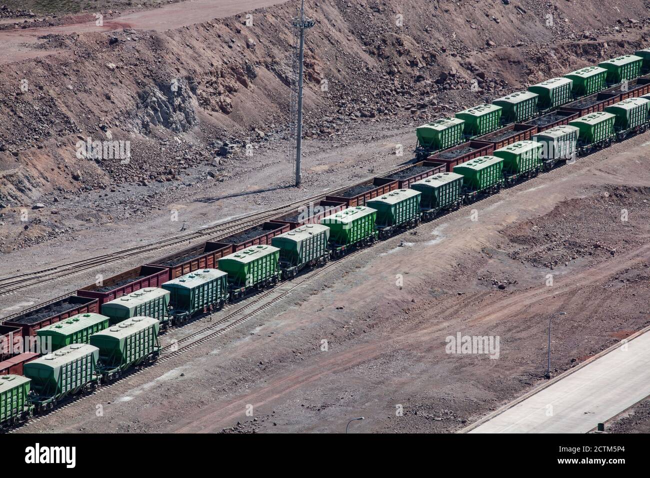 Terminal ferroviario del carico. Carrozze ferroviarie in pista. Vagoni ferroviari verdi e marroni nel deserto. Trasporto ferroviario di merci. Foto Stock