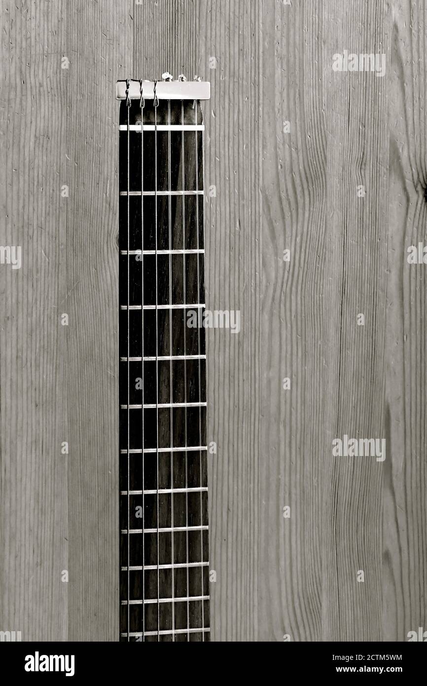 Vista aerea in bianco e nero del collo di una chitarra da viaggio su uno sfondo rustico in legno. Foto Stock