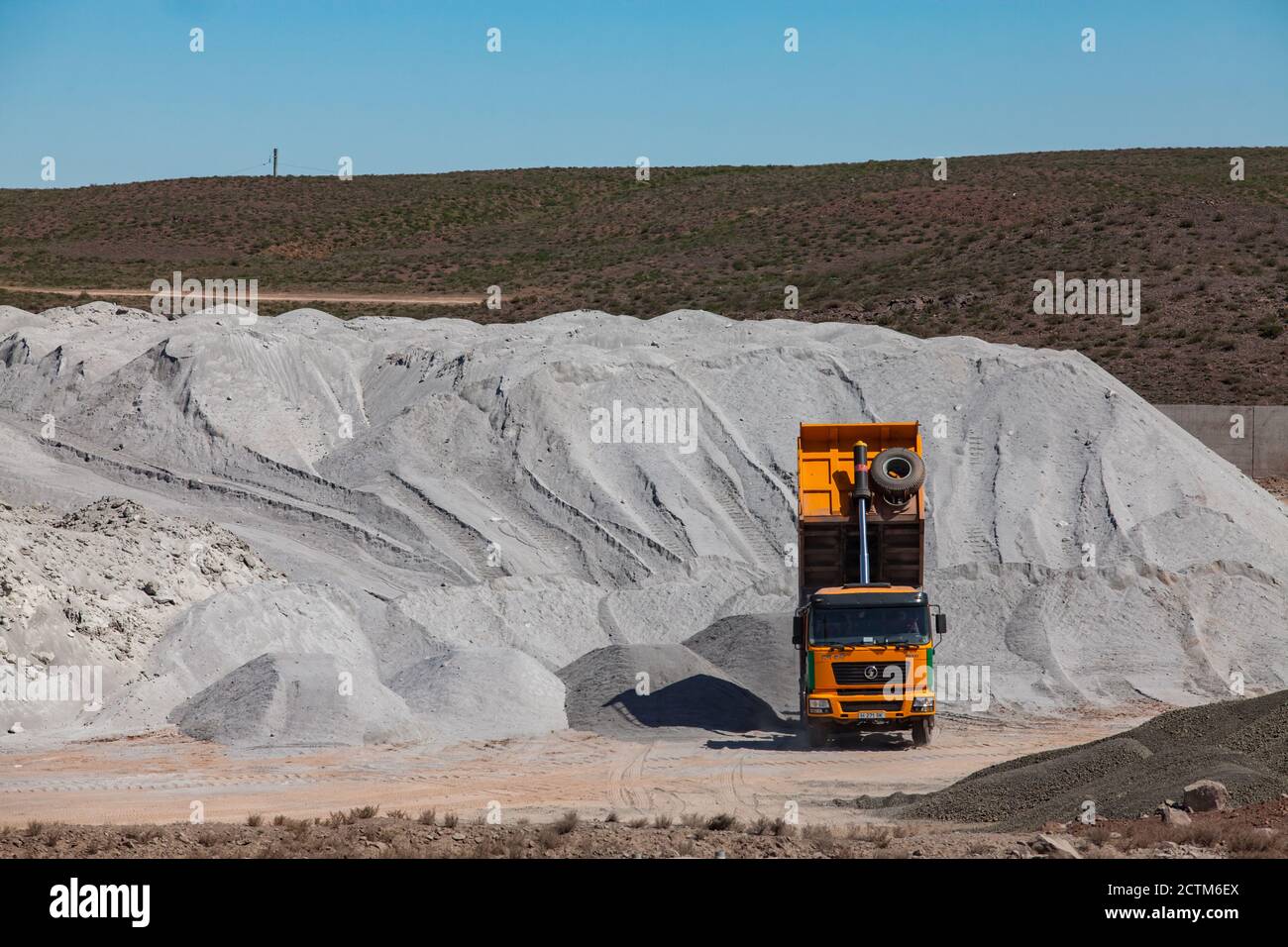 Mynaral/Kazakhstan - Aprile 23 2012: Stoccaggio di materie prime nell'impianto di cemento Jambyl. Cumulo di minerali clinker e dumper giallo. Foto Stock