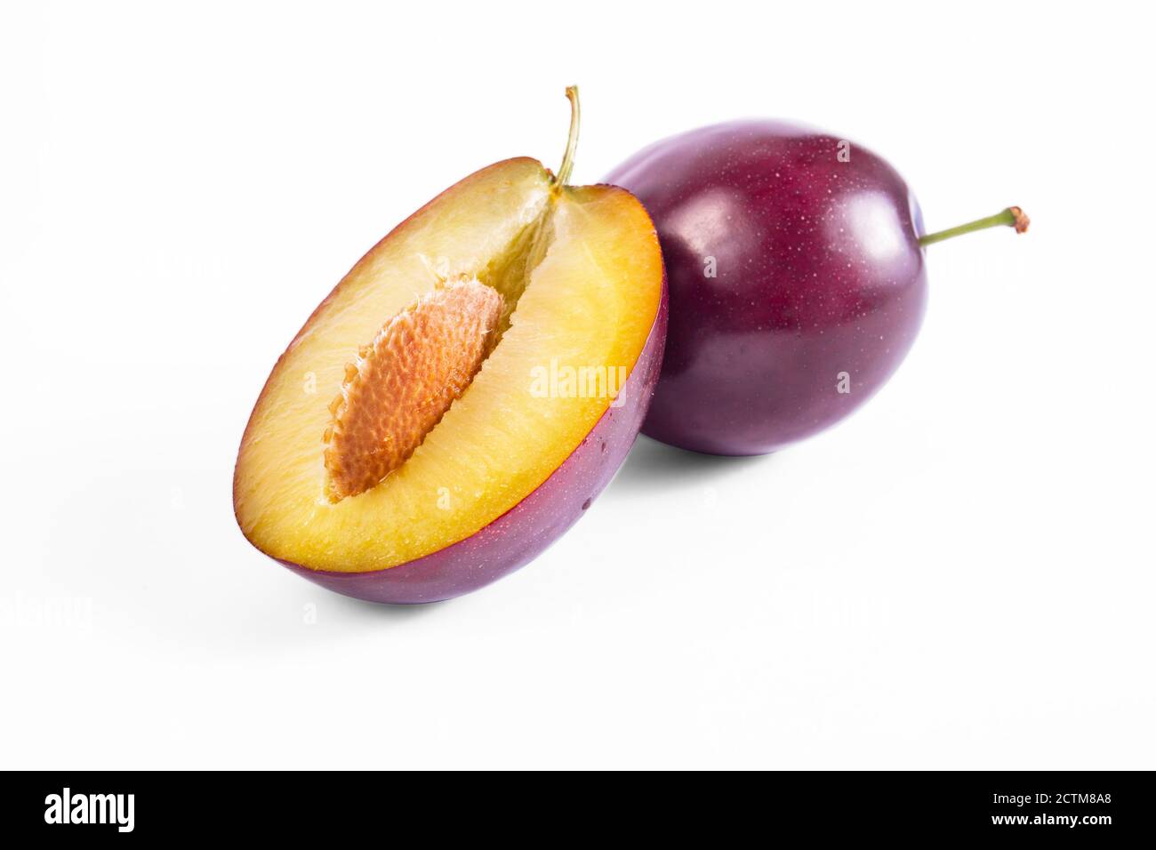 Plum mezzo frutto primo piano macro shot. Prugne dolci oragniche fresche e deliziose. Spuntino a base di frutta fresca. Isolato su sfondo bianco. Foto Stock