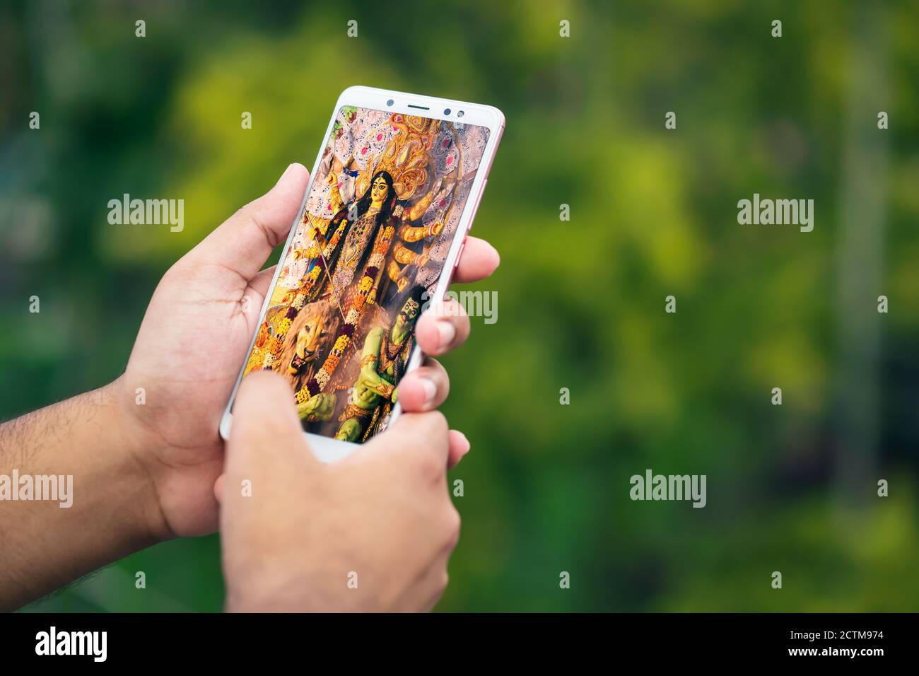Durga Puja memorie nel tempo della pandemia del virus della corona. Mano maschile tenendo smartphone e scorrendo attraverso le vecchie foto puja. 2020 Durga Puja celebrata Foto Stock