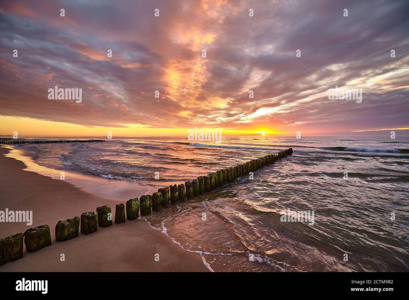 Tramonto panoramico sul Mar Baltico con una vecchia pausa in legno sulla spiaggia. Foto Stock Tramonto panoramico sul Mar Baltico con una vecchia pausa in legno sulla spiaggia. Foto Stock