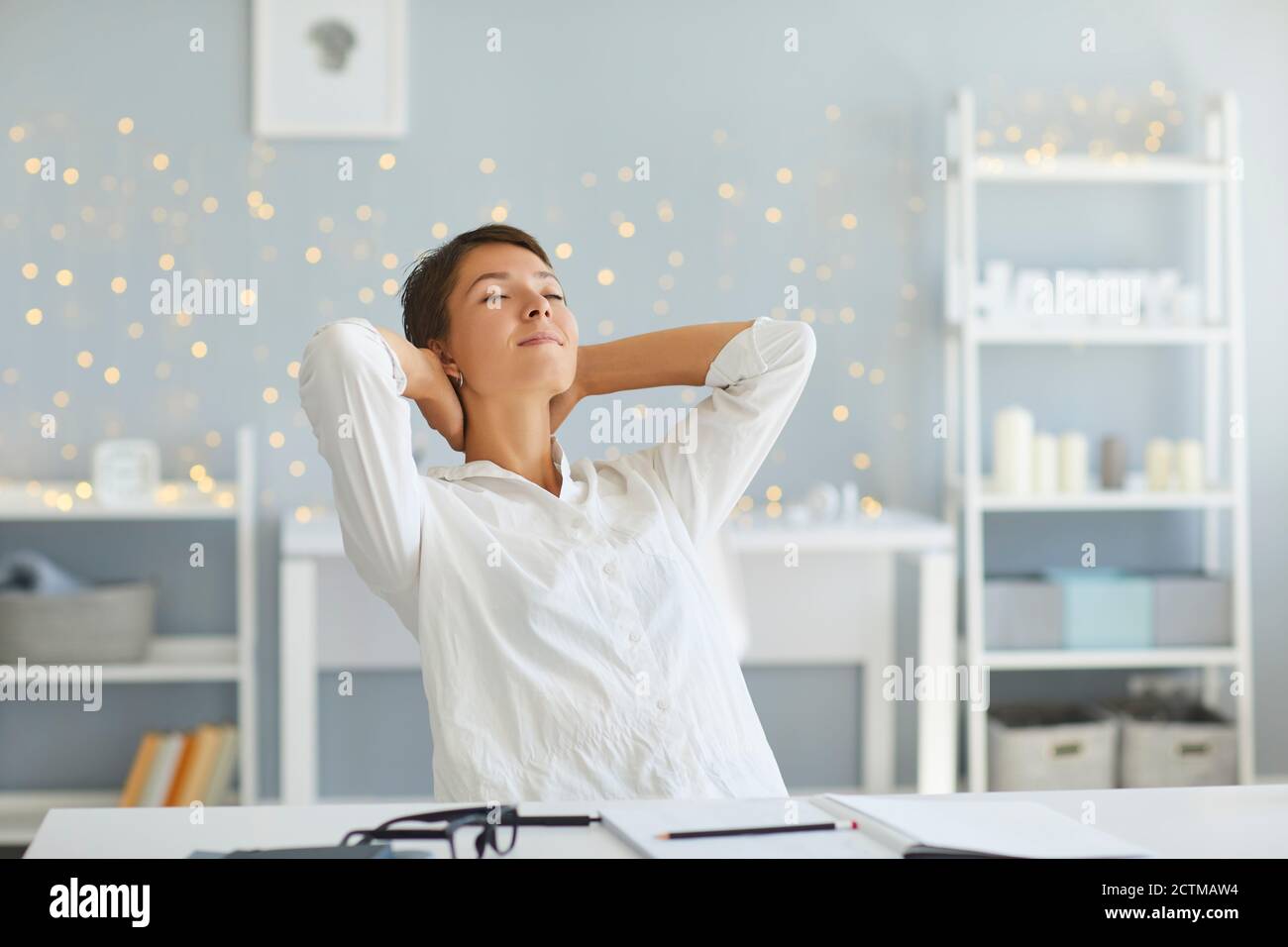 Donna rilassata nel suo ufficio domestico godendo grande senso di raggiungimento dopo la conclusione di tutte le attività quotidiane Foto Stock