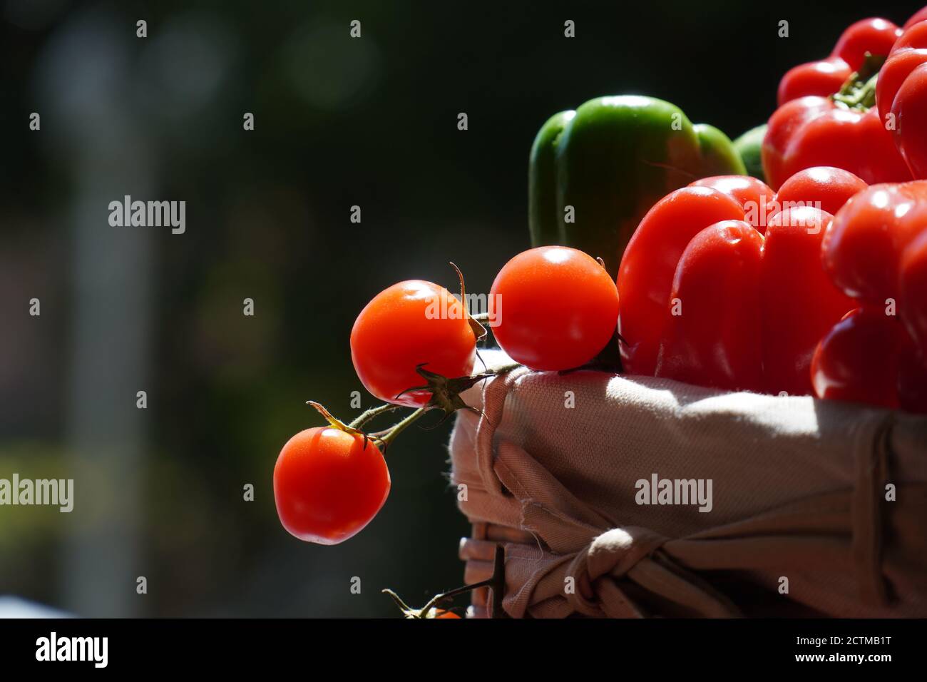 pomodori ciliegini peperoni rossi e verdure verdi in cestino Foto Stock