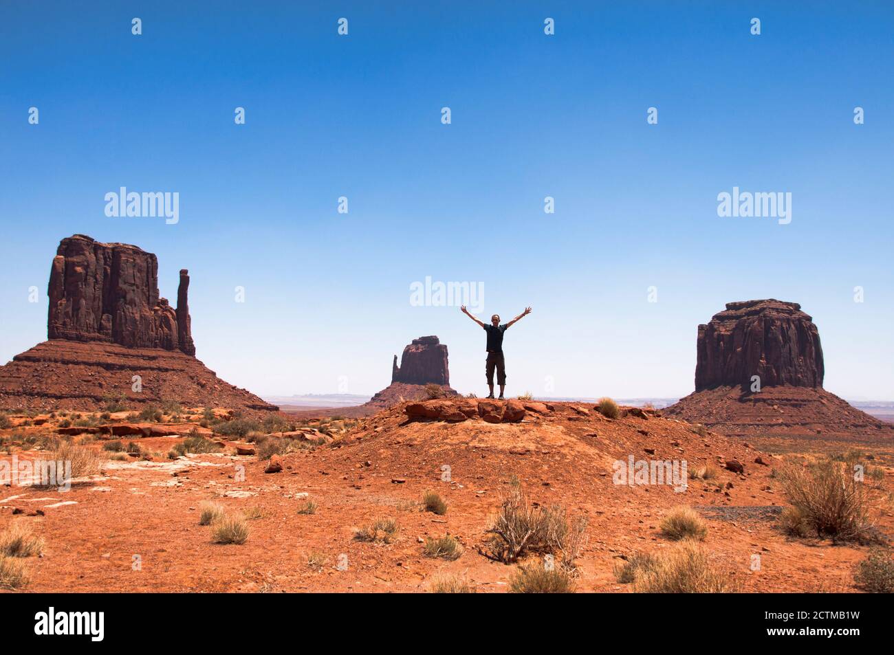 Alcuni dei famosi buttes di arenaria si trovano nella Monument Valley, una regione del Colorado Plateau nello Utah, Stati Uniti. Un giovane a braccia aperte Foto Stock