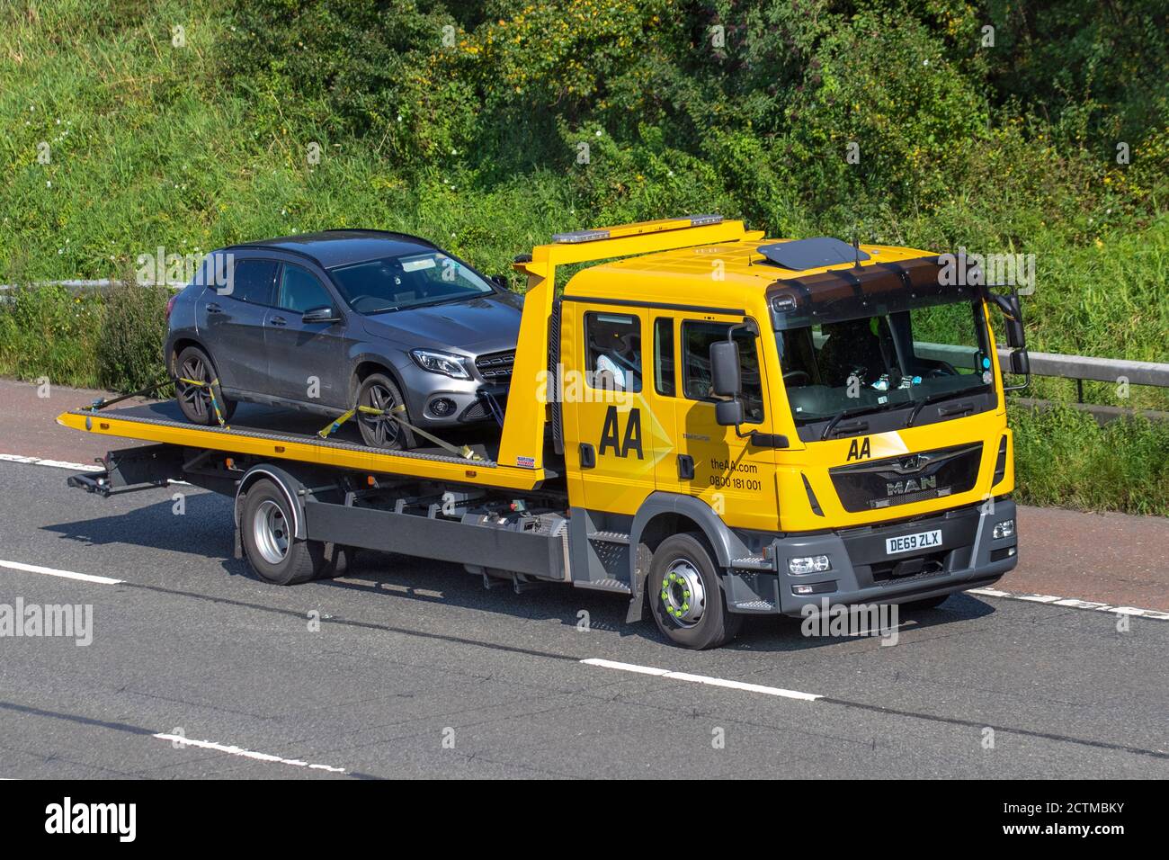 AA Roadside 24 ore di recupero guasti; trasportatore di auto uomo TGX (My2018) consegna camion, che trasporta Mercedes Benz UN trasporto di classe, camion di soccorso, carico, veicolo, consegna, trasporto commerciale, industria, sulla M6 a Lancaster, Regno Unito Foto Stock