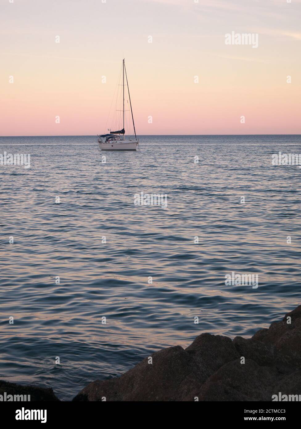 Fotografia di una barca a vela che naviga al largo del mare durante il tramonto Foto Stock
