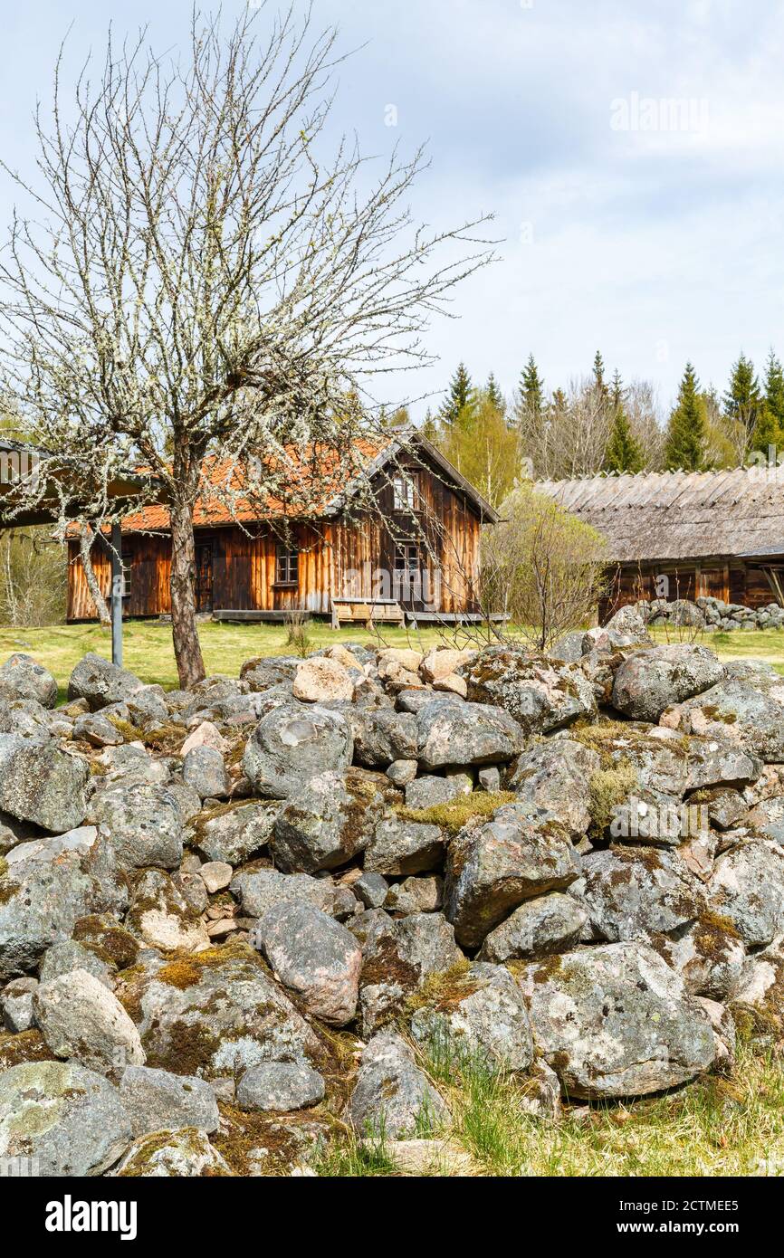 Muro di pietra in un giardino con un cottage Foto Stock