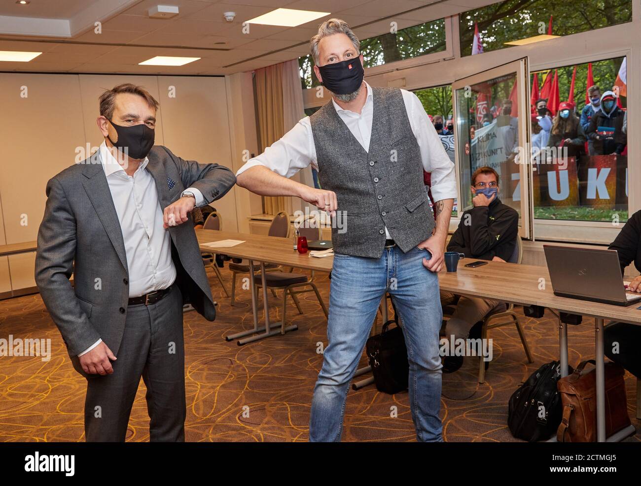 Amburgo, Germania. 24 Settembre 2020. Lars Immisch (l), responsabile delle risorse umane del Gruppo Airbus, e Carsten Bremer, negoziatore di IG Metall Küste, si danno il benvenuto in un hotel della Città Nord prima dell'inizio delle trattative collettive tra IG Metall e Airbus sulla sicurezza di luoghi e posti di lavoro. Sullo sfondo, i partecipanti ad un'azione di protesta possono essere visti davanti alla finestra dell'hotel. Credit: Georg Wendt/dpa/Alamy Live News Foto Stock