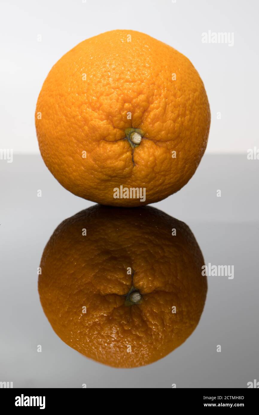 Frutta fresca. Arancione su una superficie di vetro nera che mostra il suo riflesso. Foto Stock