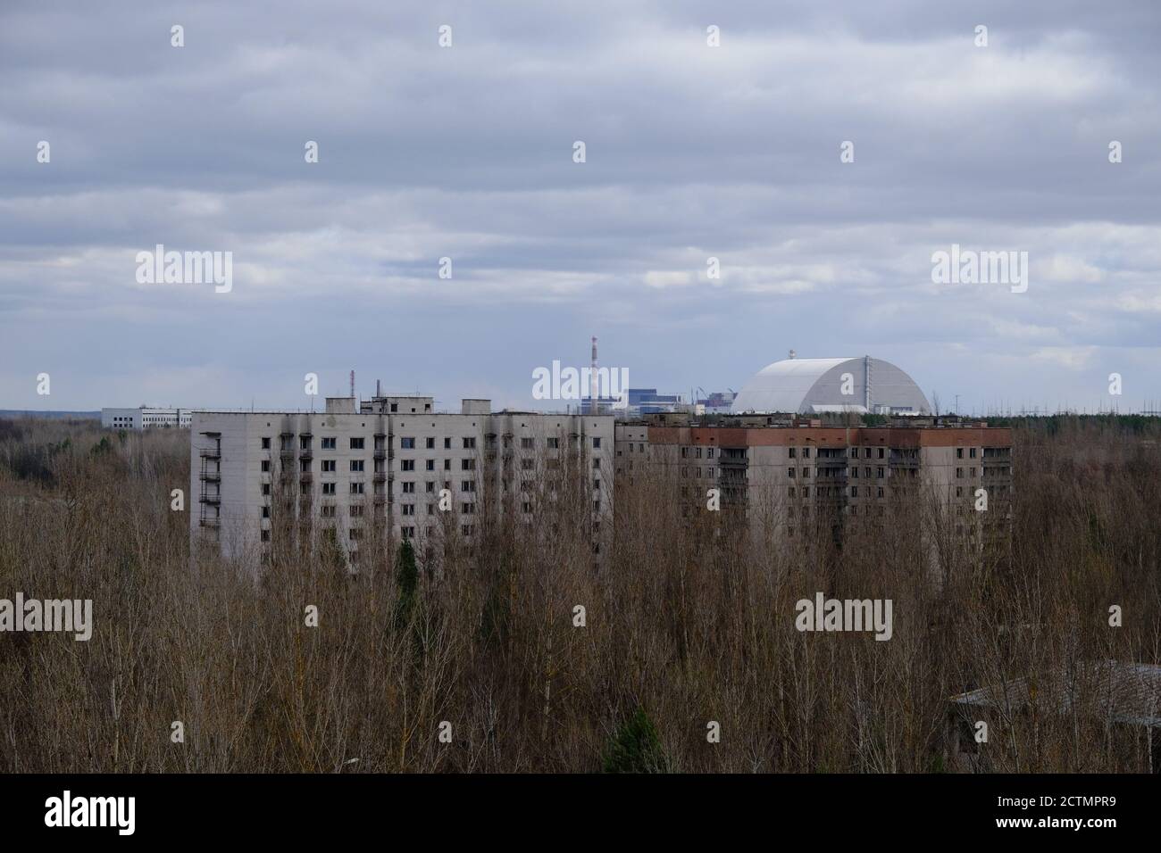 Case abbandonate a Pripyat. Centrale nucleare di Chernobyl e sarcofago protettivo sullo sfondo. Foto Stock