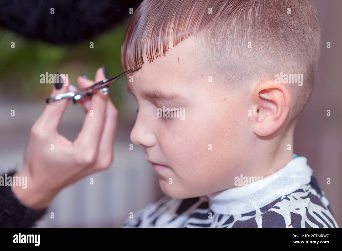 Carino giovane scolaro caucasico ottenere un taglio di capelli salon.The ragazzo chiuso gli occhi. Foto Stock