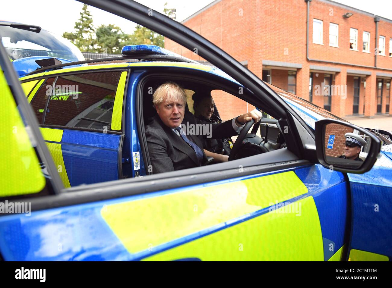 Il primo ministro Boris Johnson è seduto al posto di guida di un veicolo di polizia, con un agente di polizia nel sedile del passeggero, durante una visita alla sede centrale della polizia del Northamptonshire a Northampton. Foto Stock