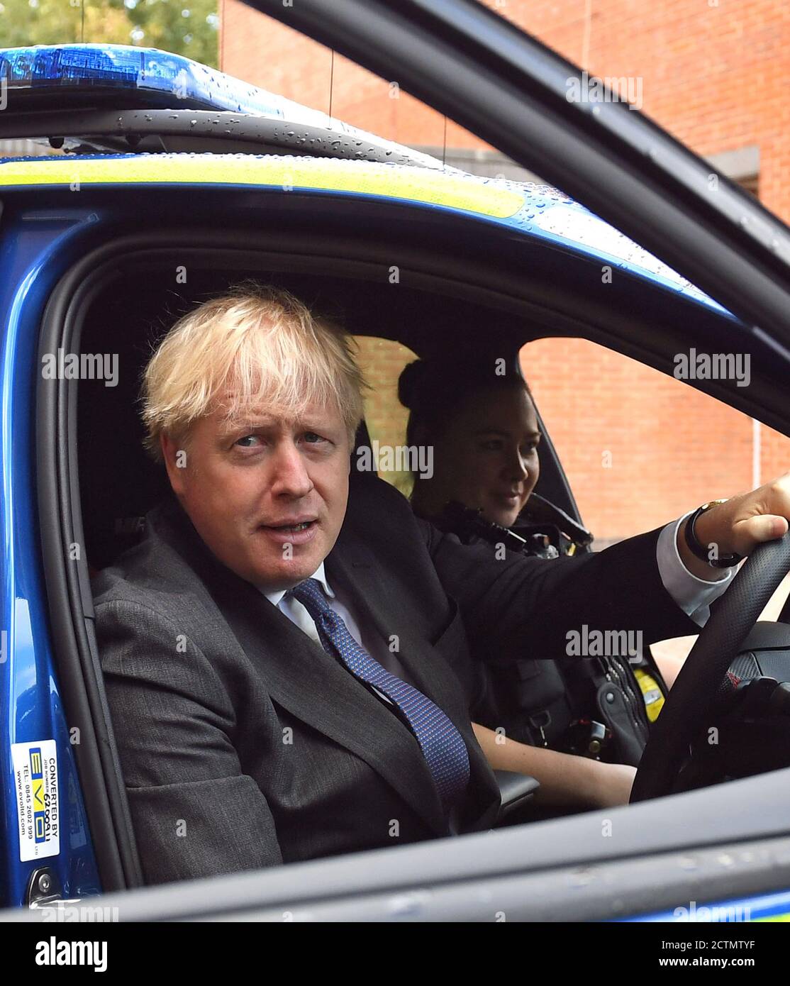 Il primo ministro Boris Johnson è seduto al posto di guida di un veicolo di polizia, con un agente di polizia nel sedile del passeggero, durante una visita alla sede centrale della polizia del Northamptonshire a Northampton. Foto Stock