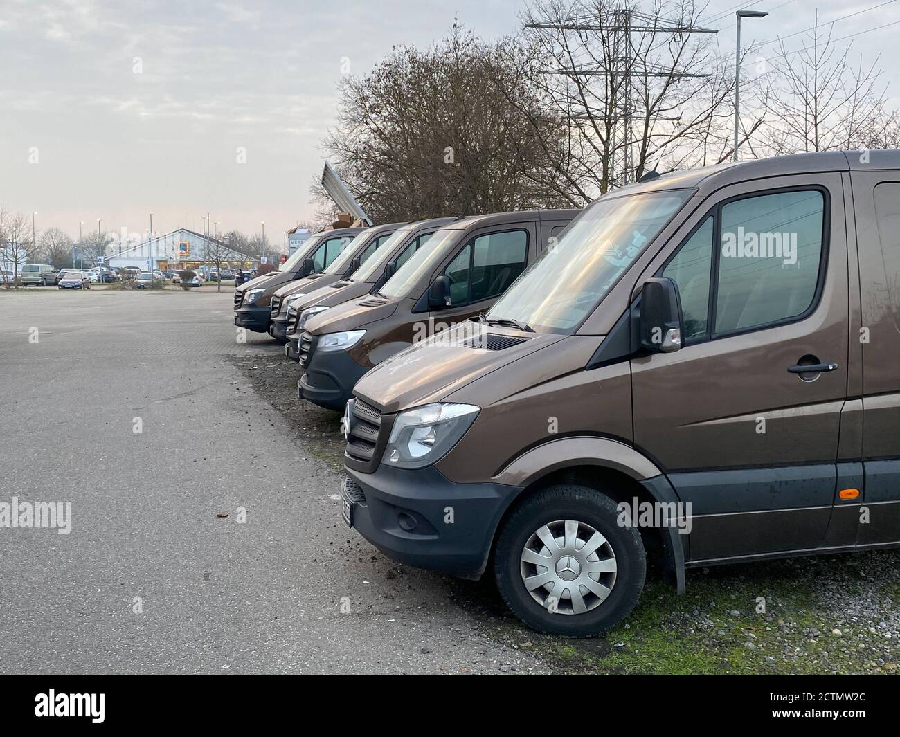 Francoforte, Germania - 25 gennaio 2020: Fila di trasporto marrone consegna  Mercedes-Benz Sprinter Electric furgoni essere parcheggiati di fronte alla  costruzione di magazzino con cielo drammatico in background - logistica  moderna per