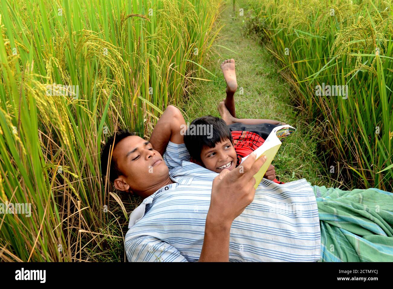 Il padre contadino passò un po' di tempo al figlio piccolo nel campo dei risaie, nel remoto villaggio indiano. Foto Stock