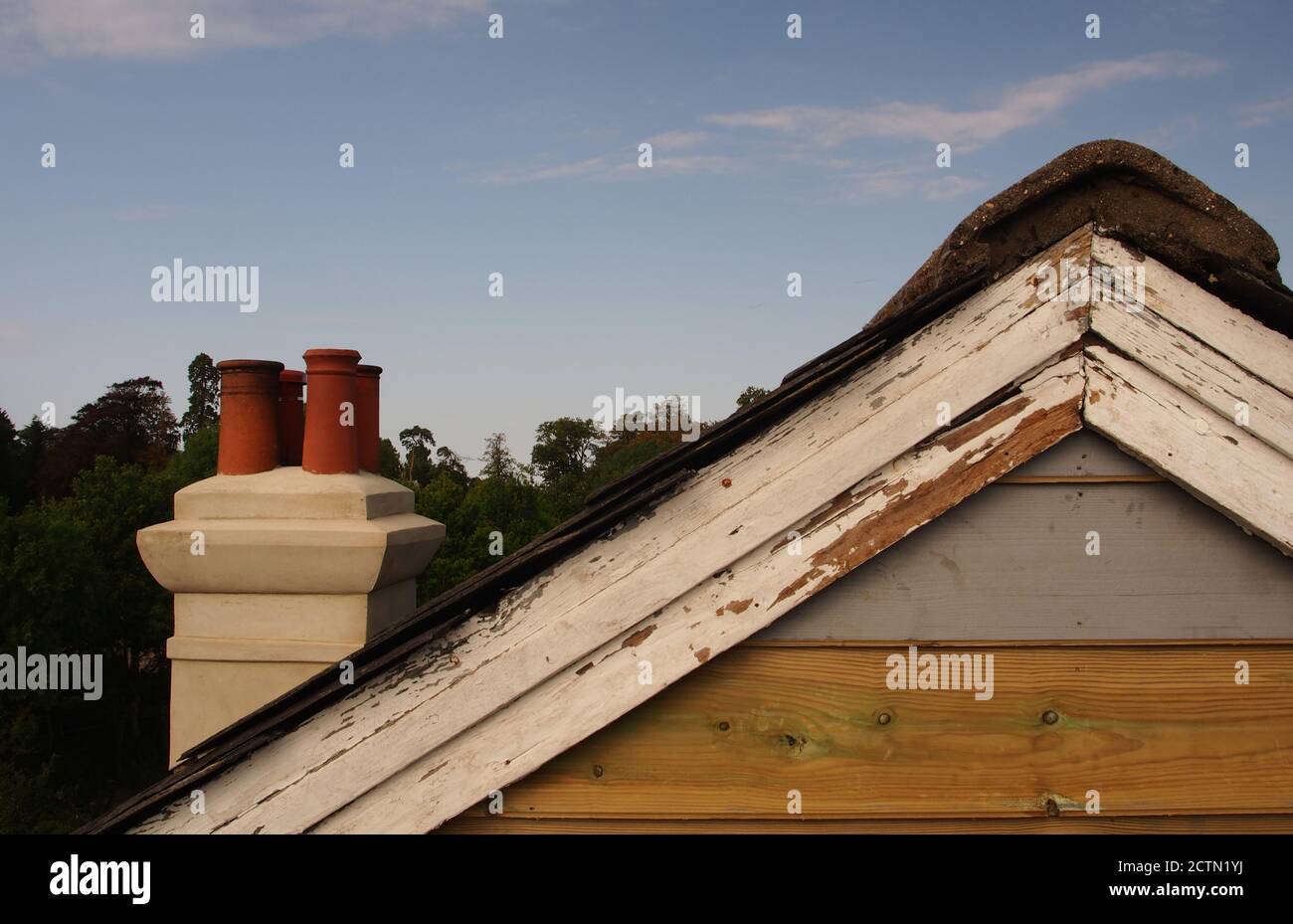 Una vista dall'impalcatura dell'estremità riparata del manto di una vecchia casa rivestita di legno, con tetto di ardesia, ancora da verniciare, più vecchie tavole di chiatta Foto Stock